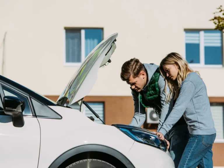 frustrated couple looking at a broken down car engine